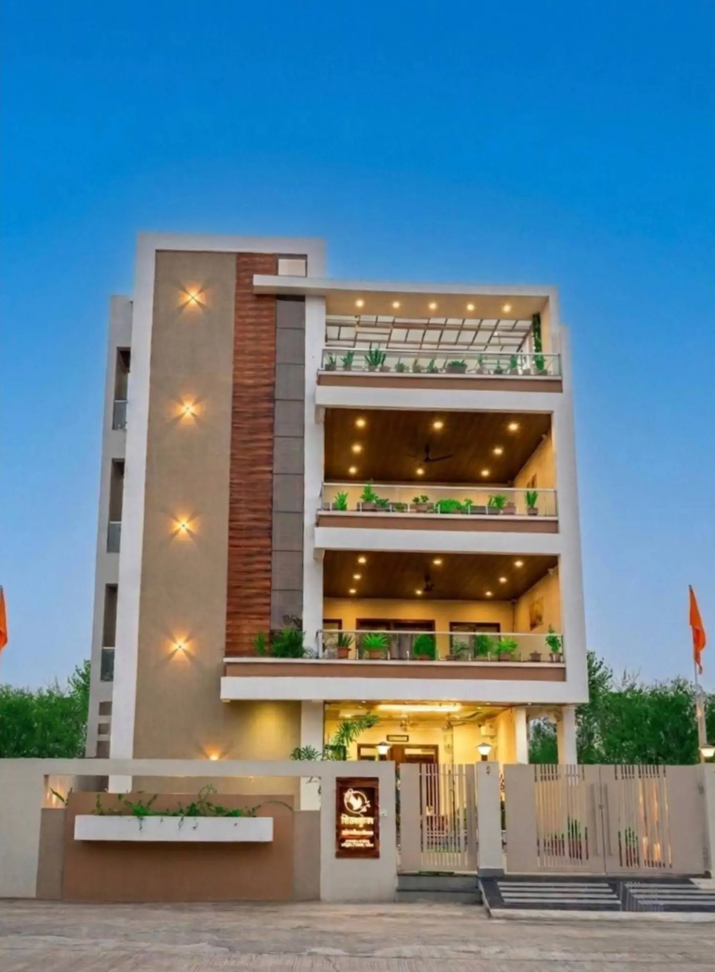 The Shivkunj hotel building at dusk, with lit balconies and plants on every floor