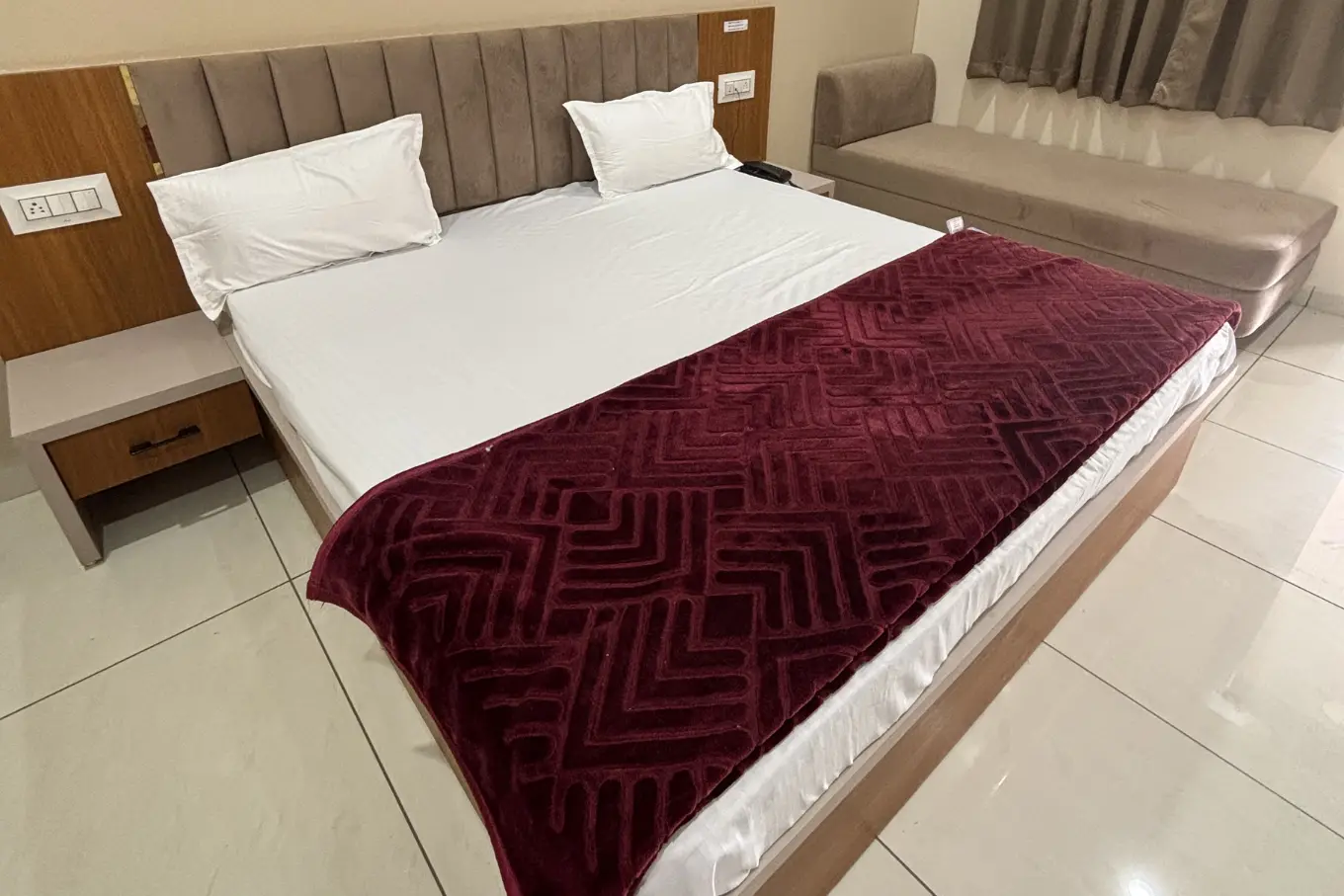 Freshly made bed with a maroon throw